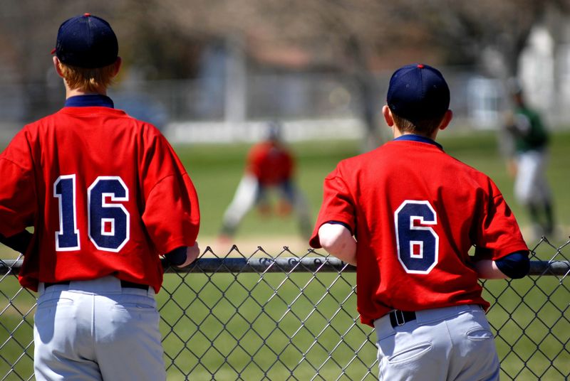 two youth baseball team members staring toward to a baseball catcher