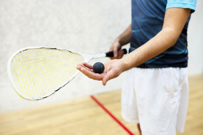 a male squash player holding a squash ball