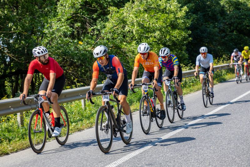 a group of cyclists on a road next to trees