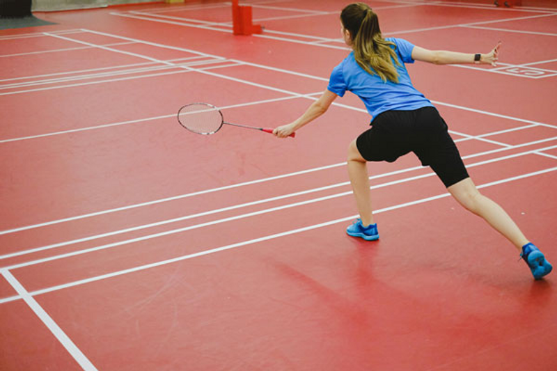 woman practicing badminton on indoor court