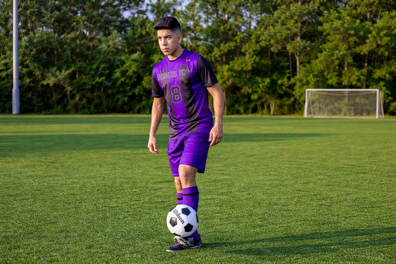 a young male soccer player wearing a purple and black soccer uniform