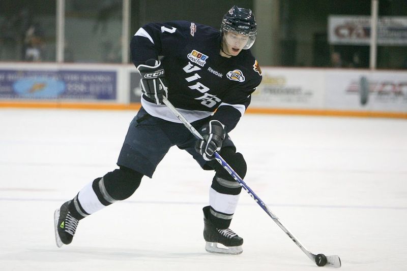 a male ice hockey player dribbling the puck