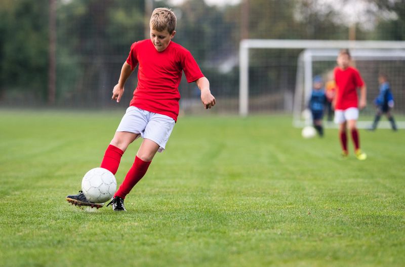 a youth soccer player kicking a white soccer ball