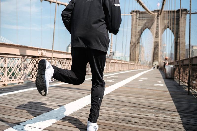 a man jogging on a bridge wearing polyester track pants