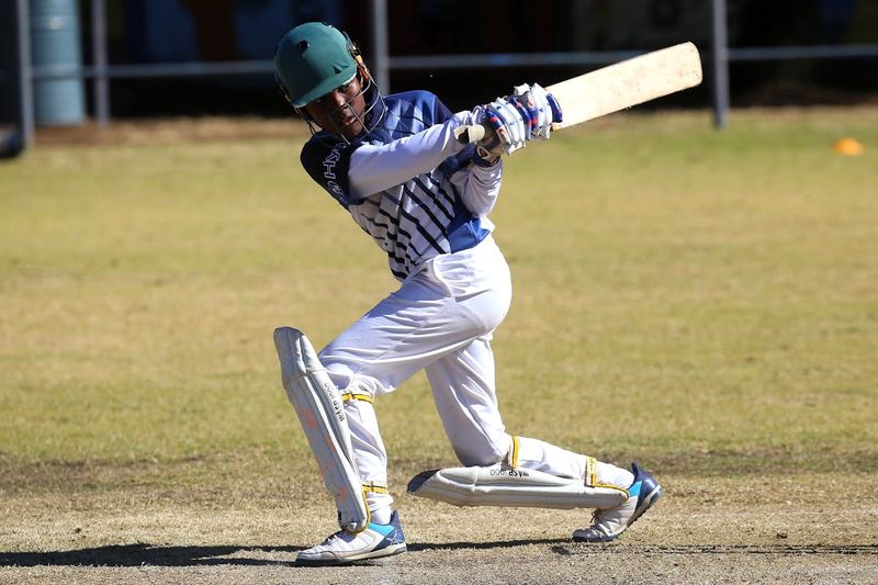 a young cricket player swinging a cricket bat