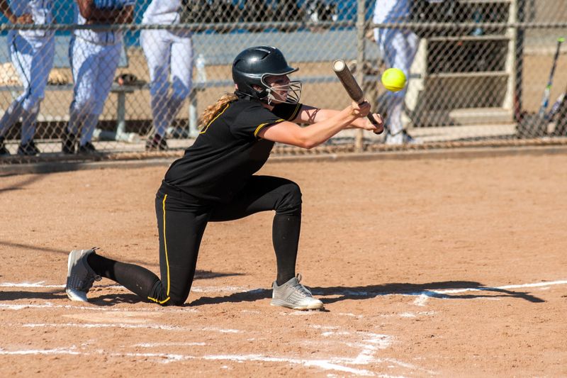 a youth softball player batting a softball pitch