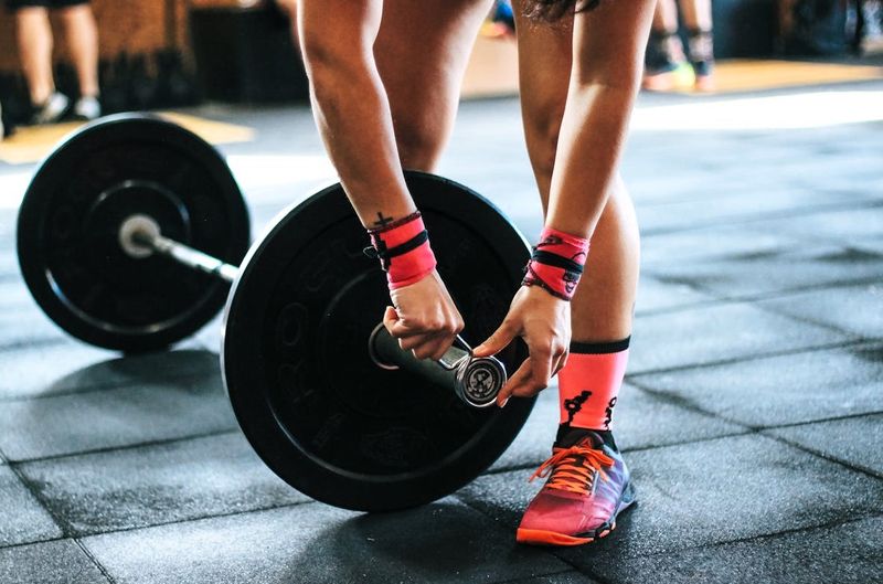 a powerlifter putting a clasp on the end of a barbell