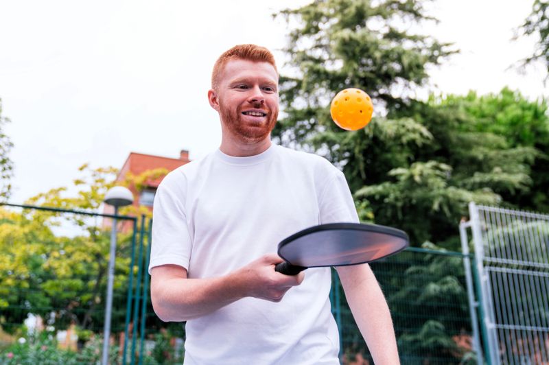 a redhead man playing pickleball