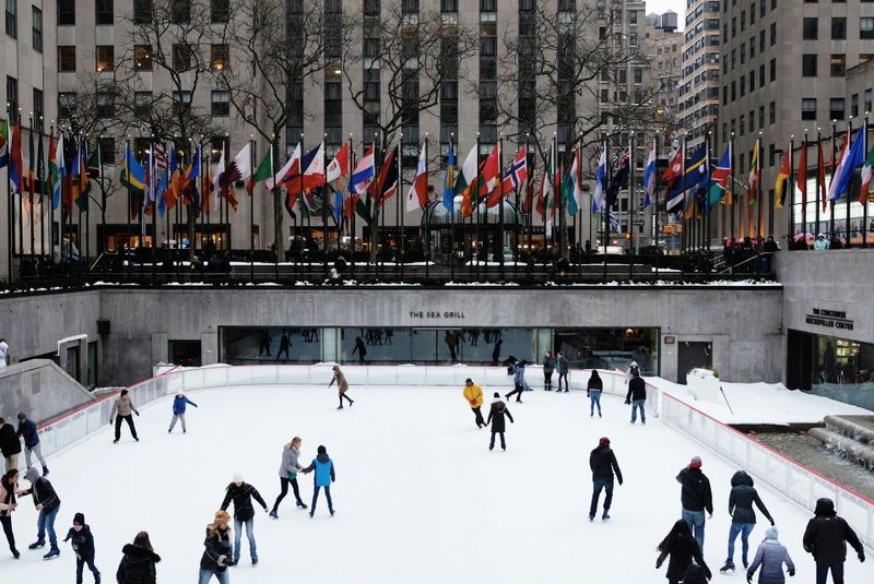 an outdoor ice rink in new york with multiple people skating on the ice