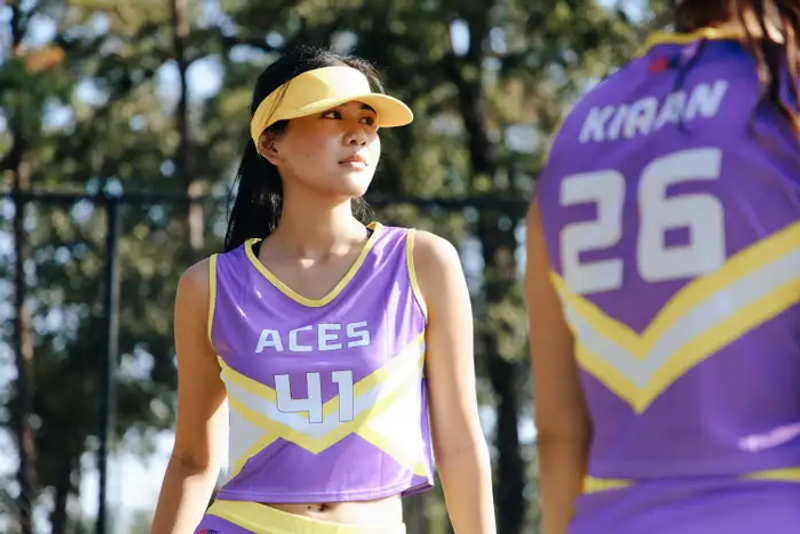 an adult female wearing a padel uniform and a visor cap playing padel outdoors