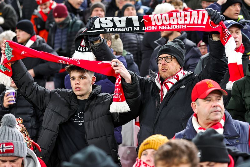soccer fans in the stands wearing winter jackets, gloves and scarves
