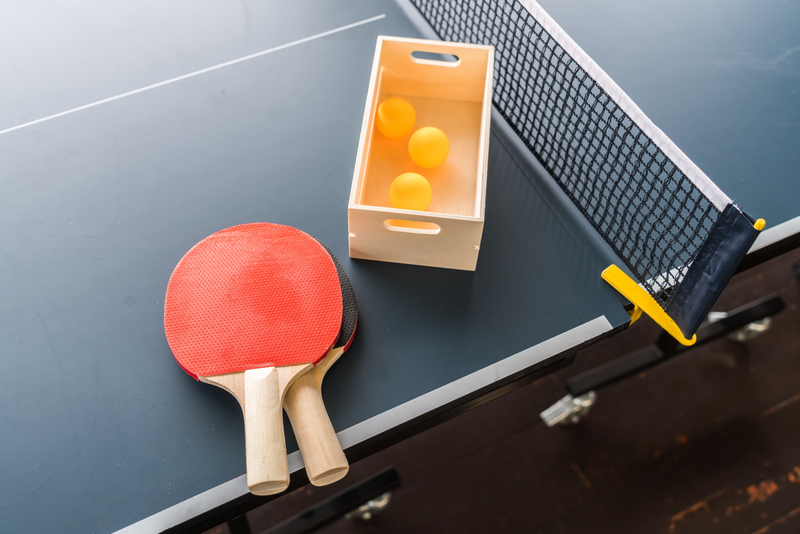 a container of ping pong balls next to a ping pong paddle