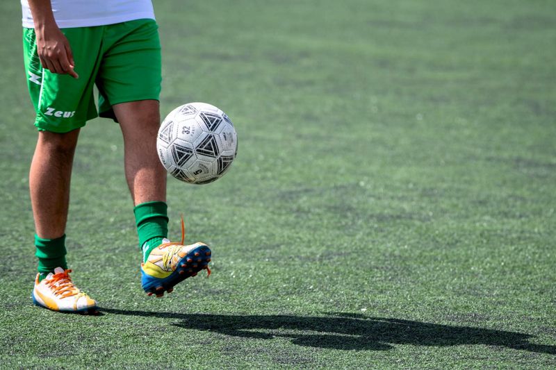 a soccer player handling a soccer ball on a turf soccer pitch