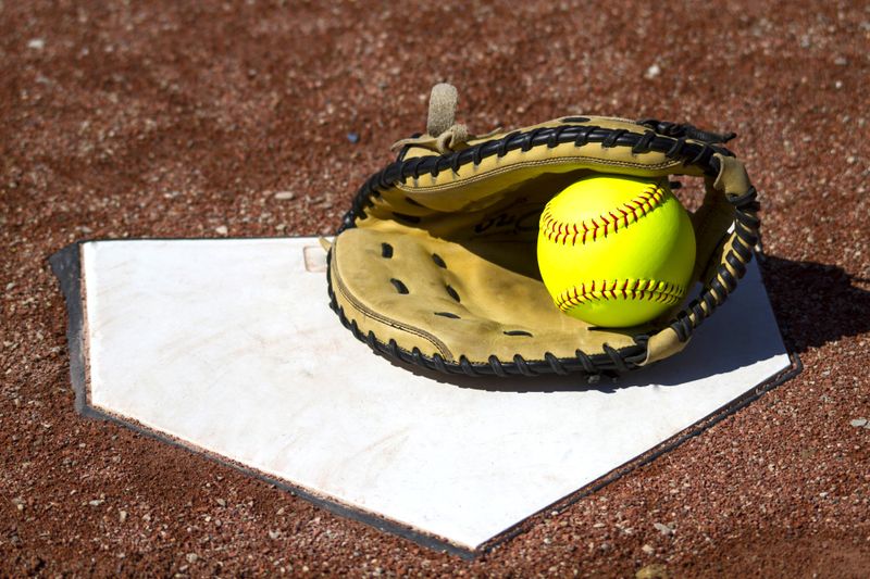 a softball gloves and softball on top of a base