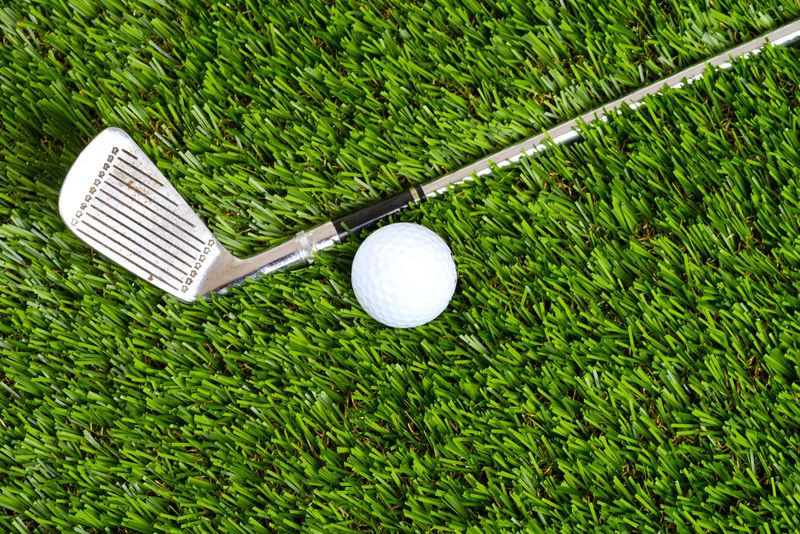 a golf wedge next to a golf ball on grass