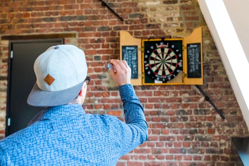 a male adult throwing a dart toward a dartboard