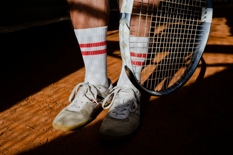 a tennis racket next to tennis shoes and socks