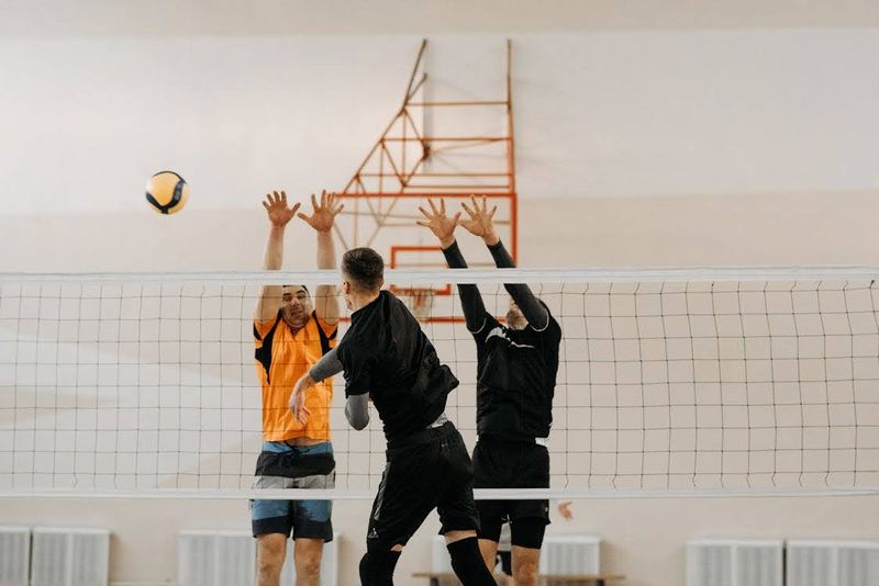 a male player spiking a volleyball over the net