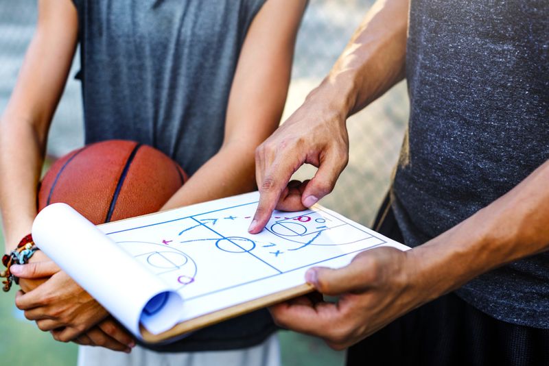 a basketball coach showing a player something on a coaches board