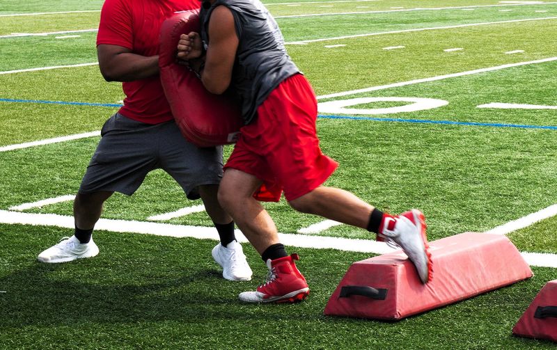 a football player in training tackling a red defensive pad