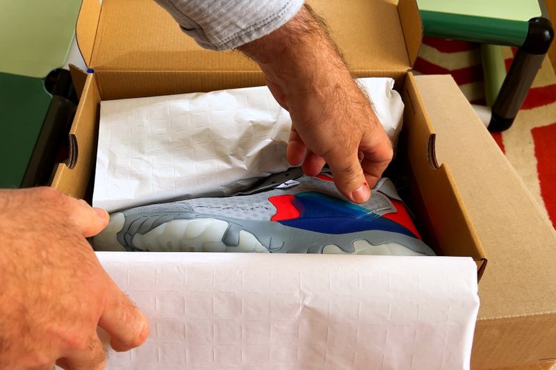 a close up of a mans hand about to remove a new basketball shoe from a shoe box