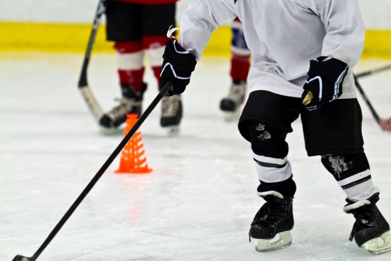 a youth hockey player skating on an ice rink holding a hockey stick