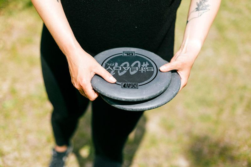 a person holding two golf discs with both hands