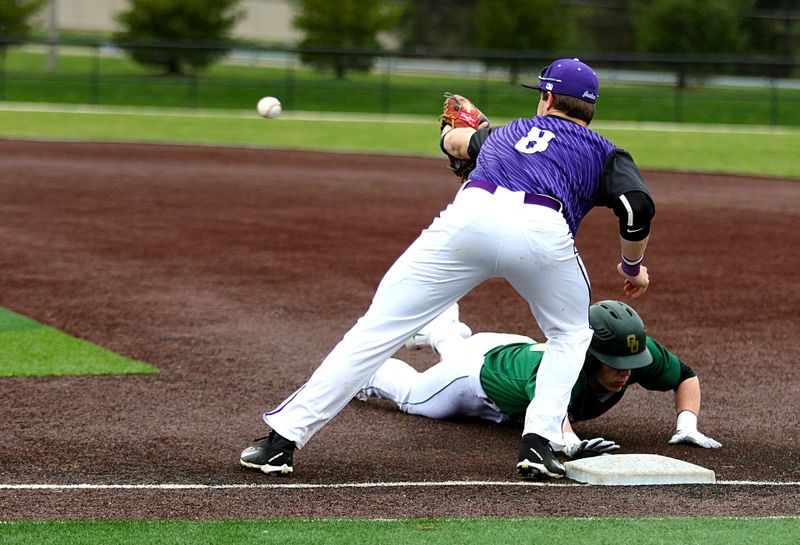 a baseball catcher about to catch a baseball with an opposing player sliding to base