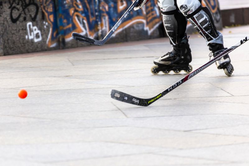 a street hockey player skating towards an orange street hockey ball