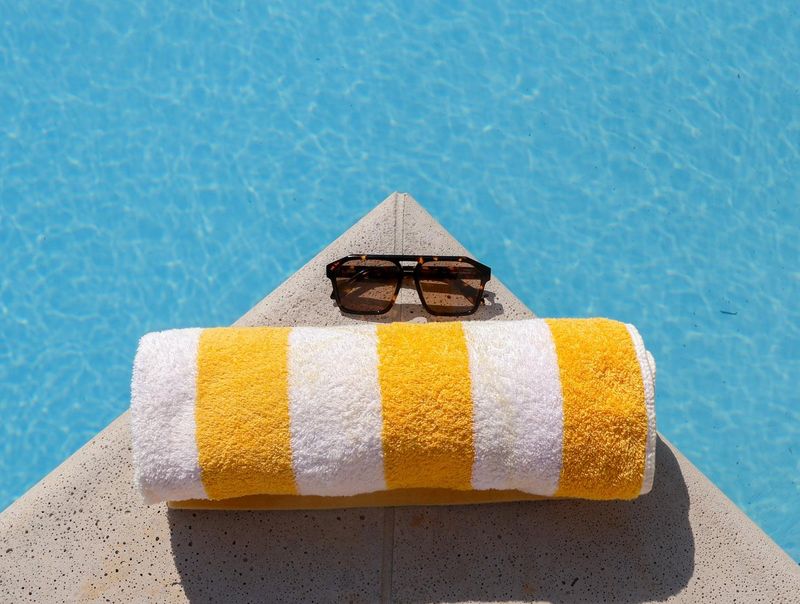 a microfiber towel and sunglasses on the ledge of a pool