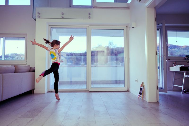 a young girl practicing cheerleading at home while recording herself on an tablet