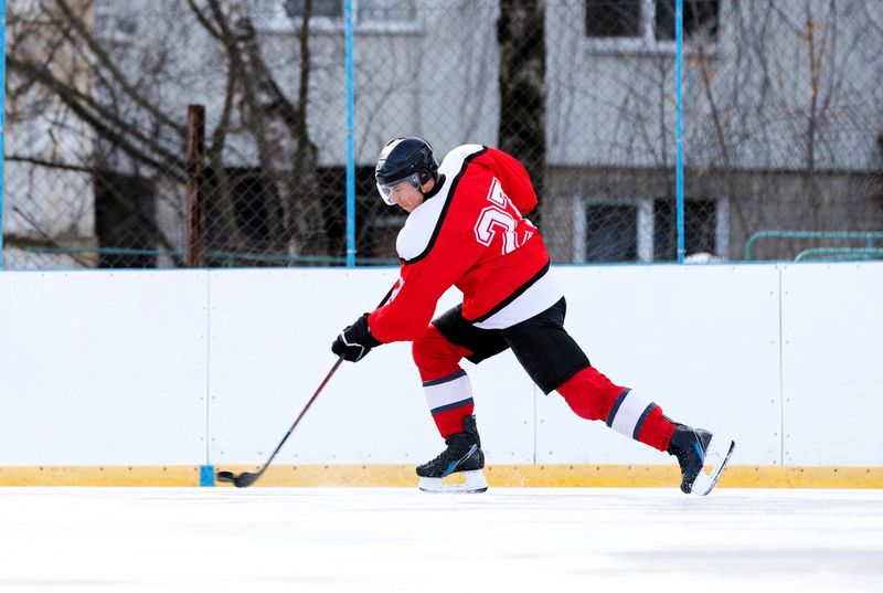 a male adult hockey player dribbling the puck on an outdoor ice rink