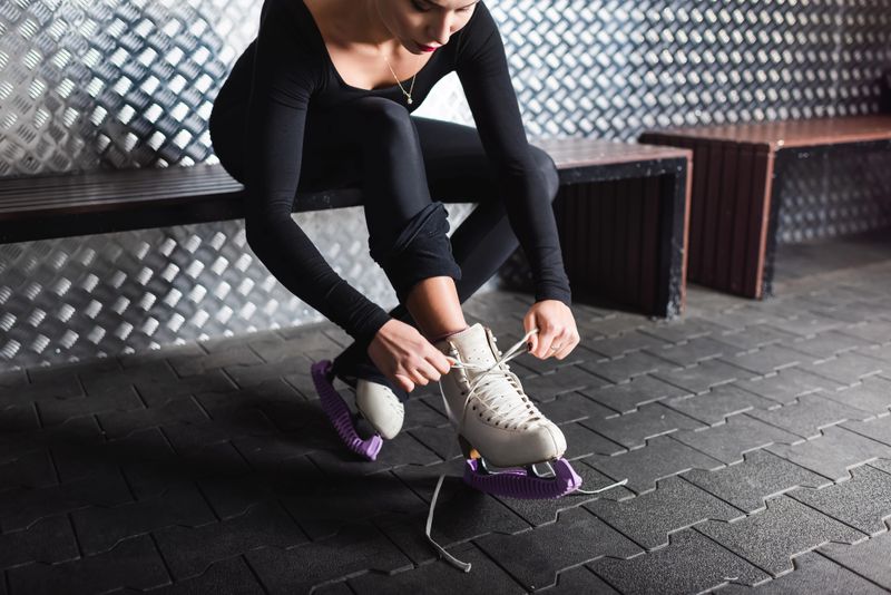an adult female tying laces on her ice skates