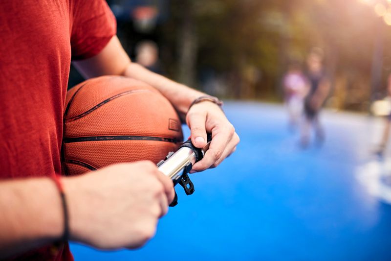a man in a red shirt pumping air into a basketball