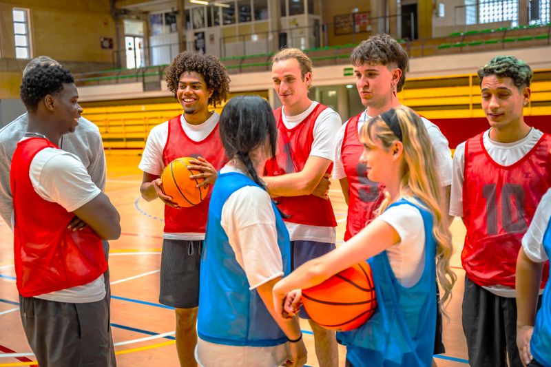 a group of basketball players wearing white shirts under basketball pinnies on a basketball court