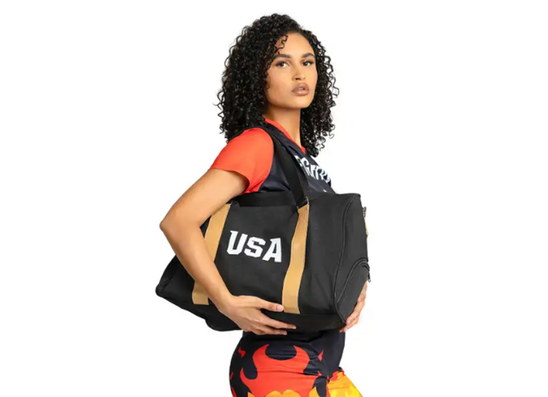 an adult female holding a black duffle bag that shows the text USA on the side of the bag