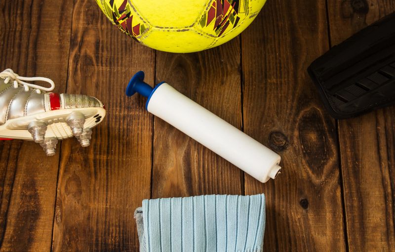 a soccer ball pump in the middle of other soccer gear on a wooden table