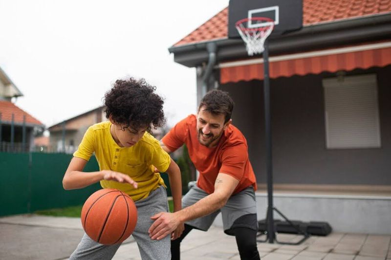 an adult and child playing basketball in front of a garage door