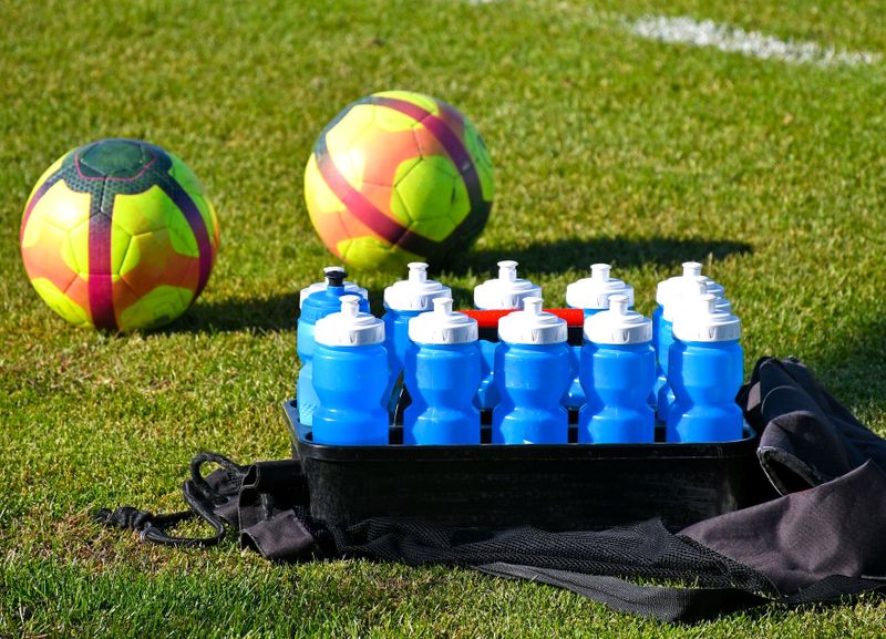 soccer team water bottles and soccer balls on a pitch