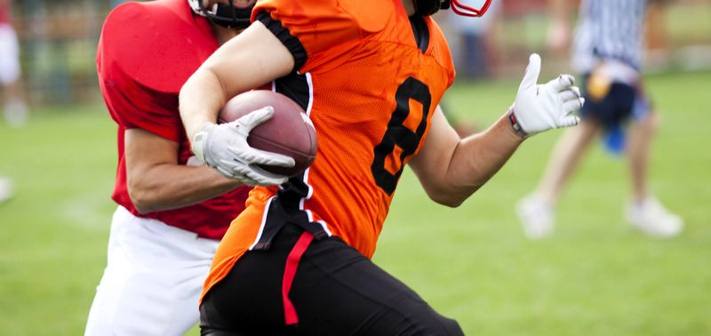 two football players wearing football gloves running on grass