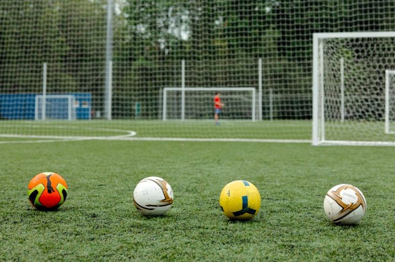 four different soccer balls in front of a soccer goal