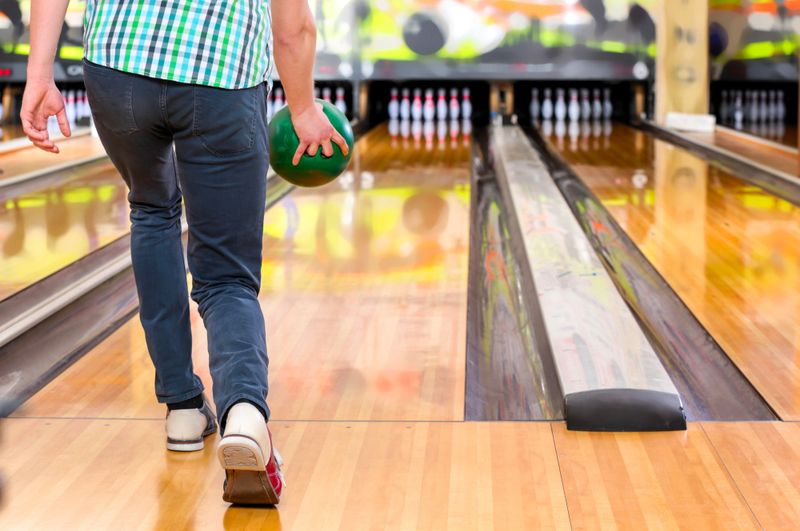 an adult male holding a bowling ball taking a step toward the lane