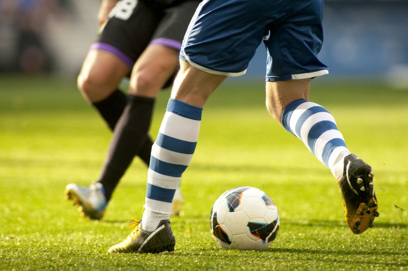 a soccer player handling a soccer ball in front of an opponent