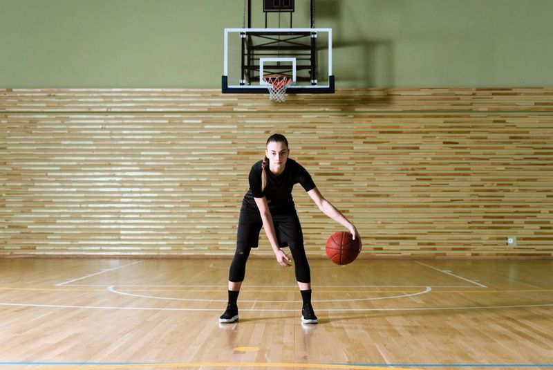 a youth female practicing stationary basketball dribbling