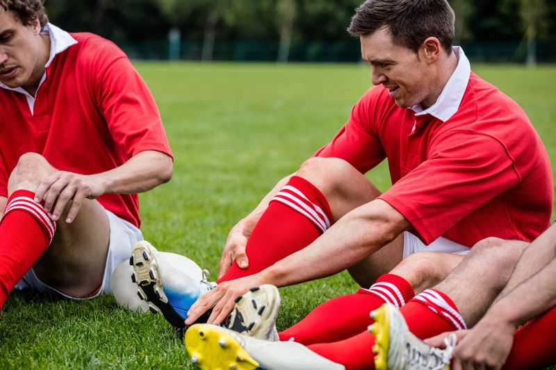 rugby players sitting on grass adjusting their cleats