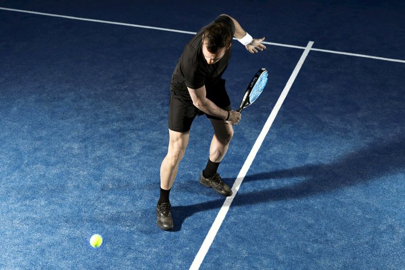 an adult male about to hit a padel ball 