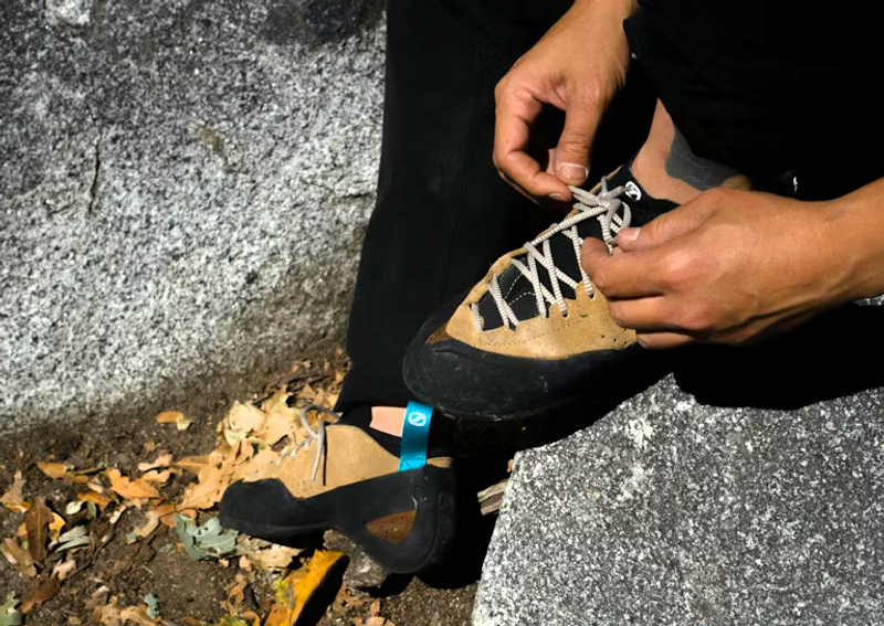 a hand tying laces on climbing shoes