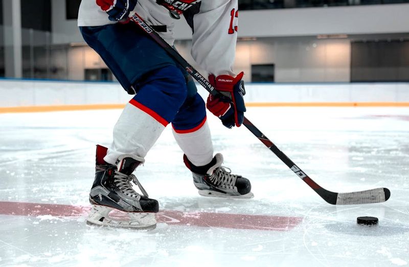 an ice hockey player dribbling a hockey puck