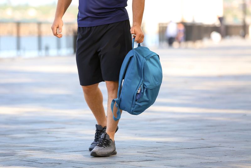 a man carrying a blue backpack in one hand