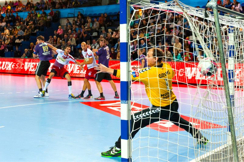 a handball goalie stretching to save a shot